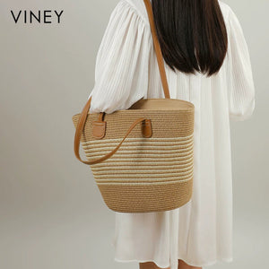 Model carrying VINEY striped woven straw tote over one shoulder, rear view