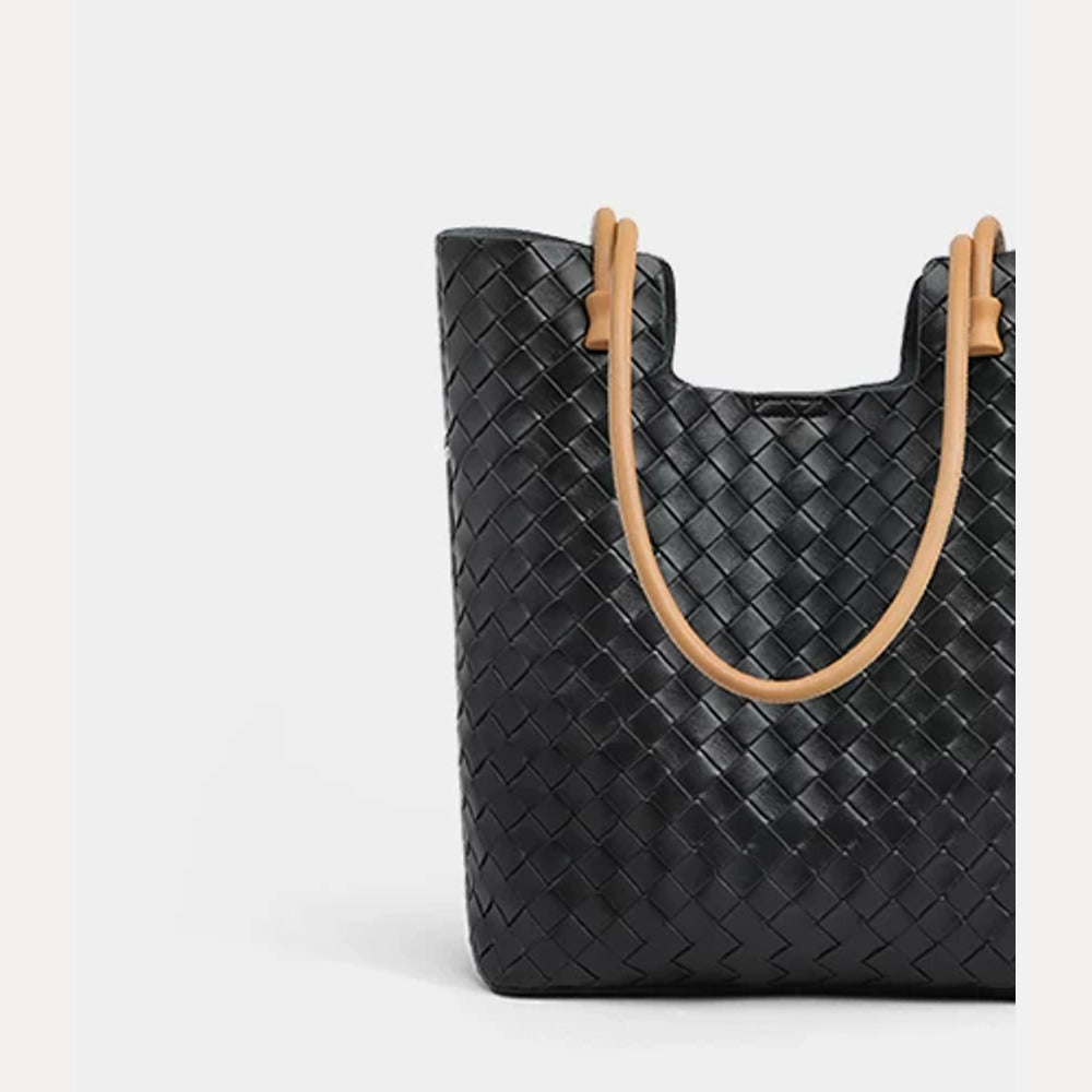 Close-up front view of black woven leather tote with tan shoulder straps