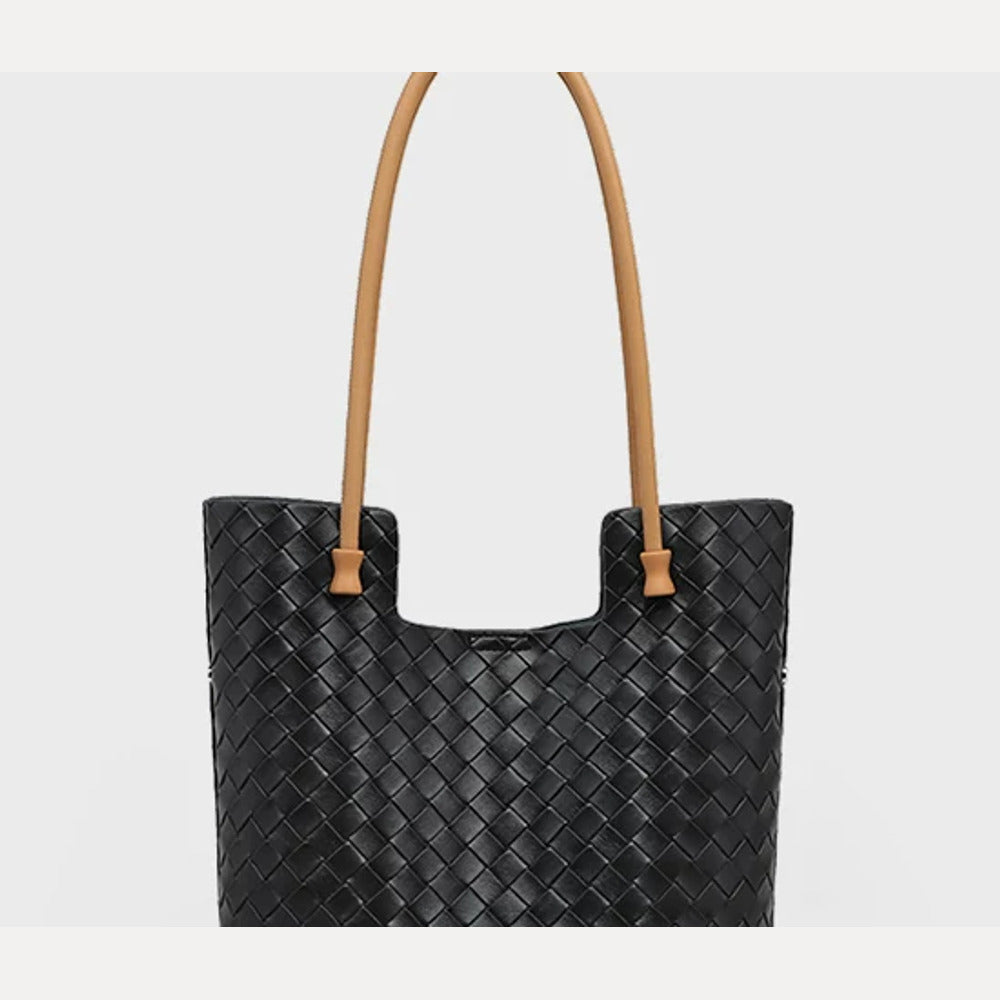 Upper front of black woven leather tote showing tan shoulder straps and woven texture